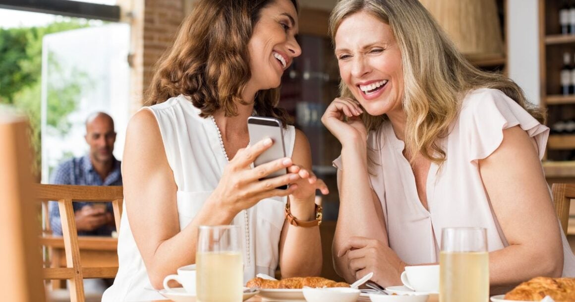 a couple of women looking at a phone