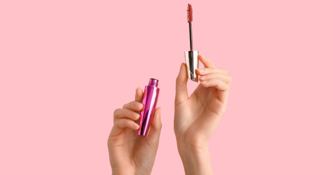 Hands holding mascara tube and wand